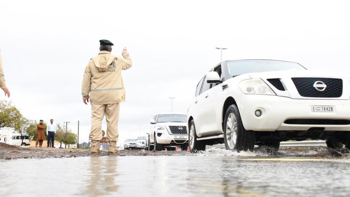 A police officer controls traffic on a flooded street in Dubai.