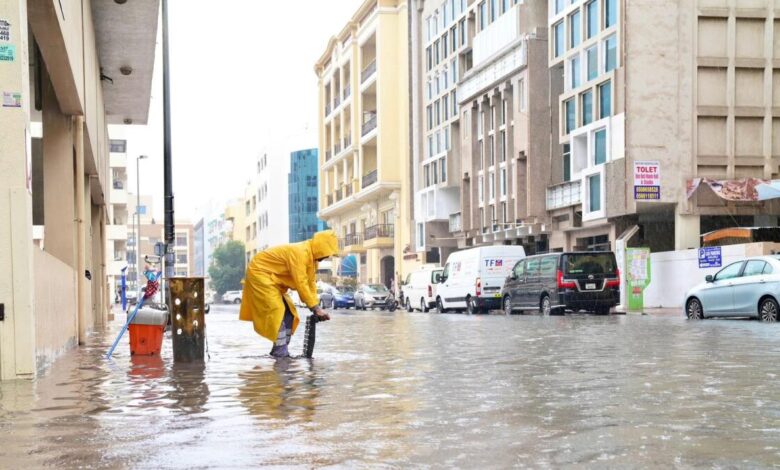 A Dubai Municipality employee works to clear water from a street after heavy rain on Saturday.  — Photos: supplied