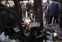 People gather around the carcass of a car used by US-based aid group World Central Kitchen, that was hit by an Israeli strike the previous day in Deir Al Balah in the central Gaza Strip on April 2, 2024.